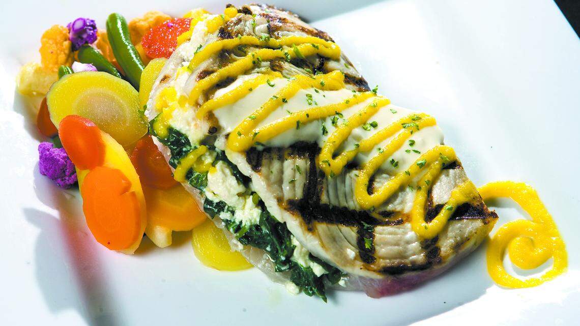 The grilled swordfish stuffed with spinach and feta cheese is accompanied by a colorful medley of fresh vegetables.
