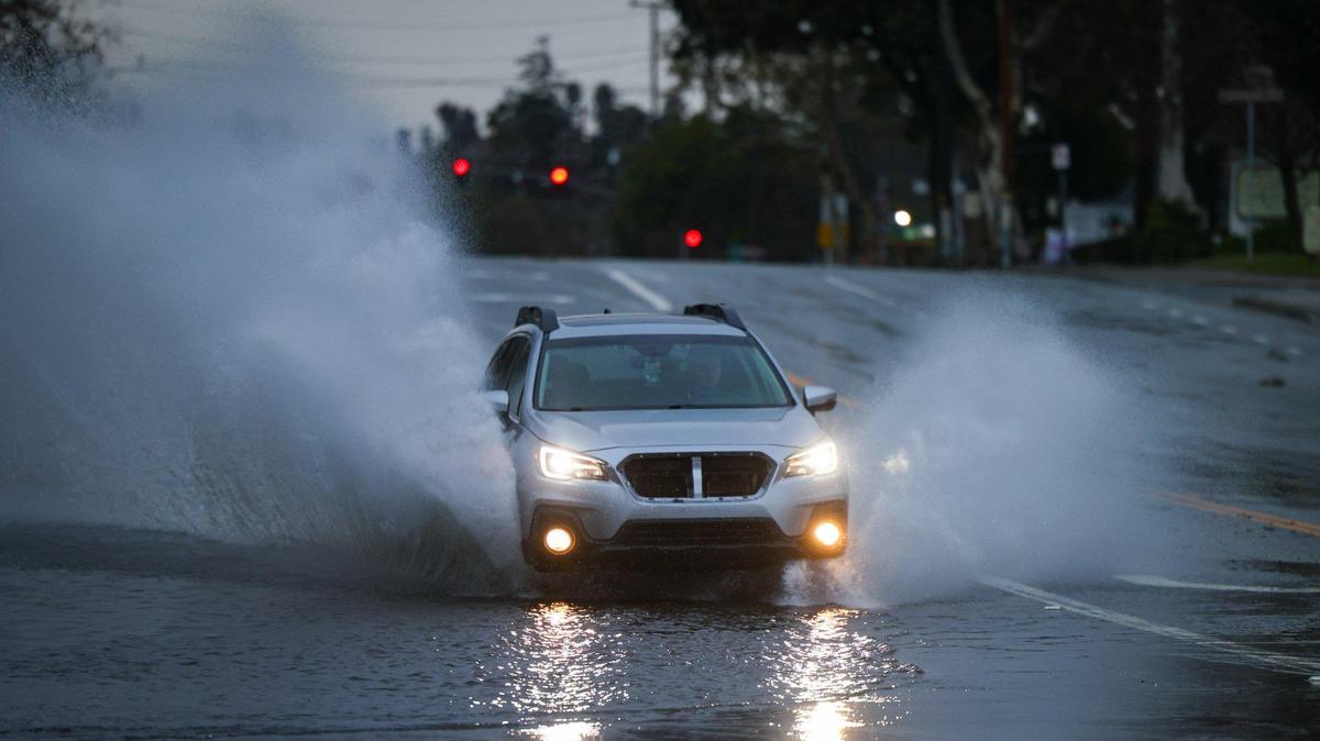 A car splashes through a flooded section of Broad Street at Story Street in San Luis Obispo on Friday, Feb. 24, 2023.