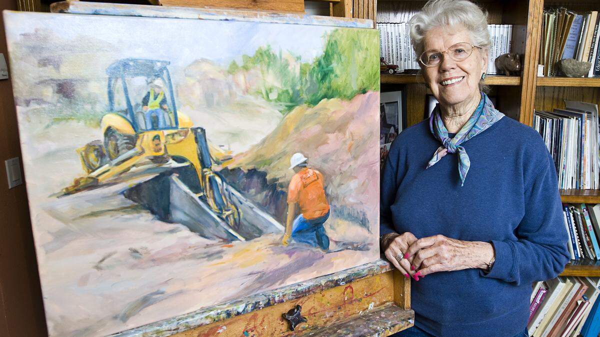 Joan Sullivan is shown here with one of the paintings from her ‘Pipe Layers’ series documenting the ongoing sewer project happening in Los Osos. This painting is titled ‘Back Hoe Pulling Out a Shield.’