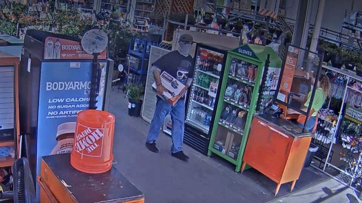 A surveillance photo shows the suspect carrying a power tool up to the register at the Atascadero Home Depot on Aug. 6, 2022. Police say the suspect demanded money and showed the handle of a gun before leaving the store with the power tool.