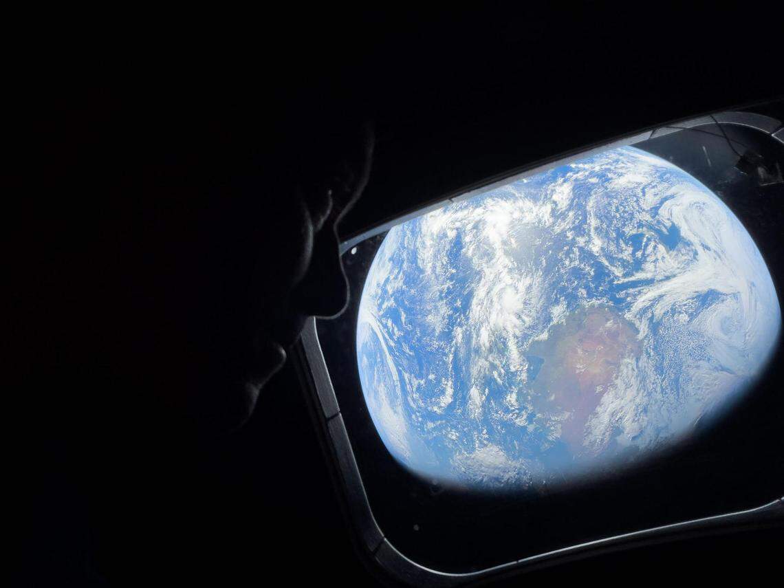 NASA astronaut and Artemis II Commander Reid Wiseman peers out of one of the Orion spacecraft’s main cabin windows, looking back at Earth on April 4, 2026,, as the crew travels towards the moon.