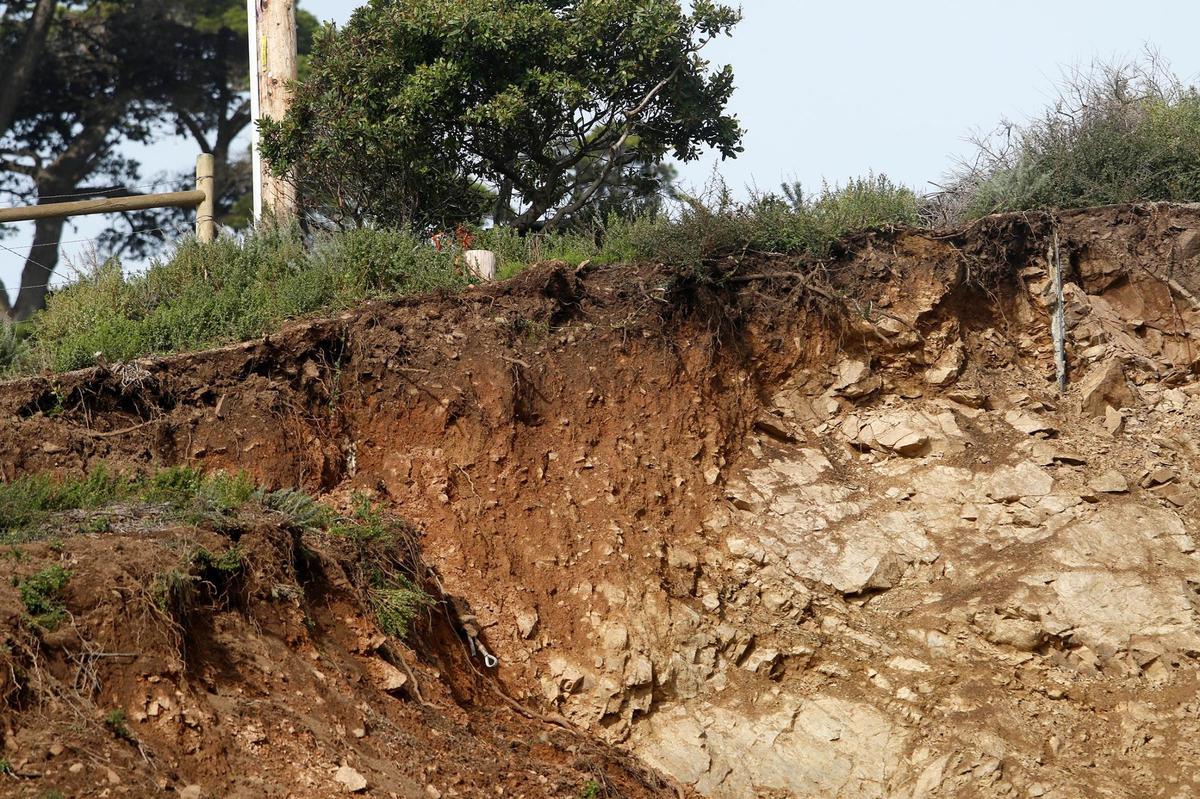 Mesh was unable to contain a rock slide that slipped onto Highway 1 at Polar Star, about a mile south of Ragged Point, seen here on Jan. 5, 2023. A fence railing is seen in the backyard of a home at the top of the slide.
