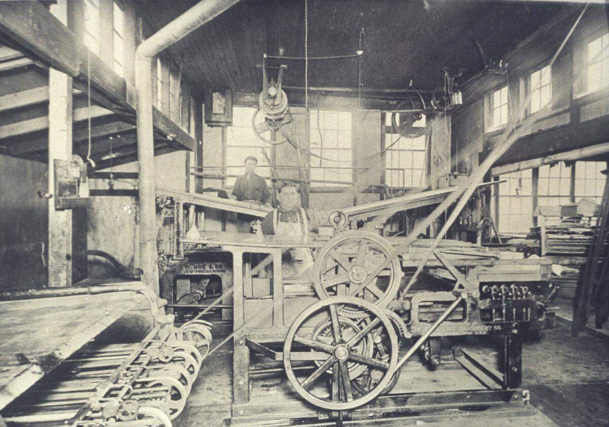 This was the old Tribune press room when it was located on Chorro Street where the new home of the Union Hardware company stands. At the press in the foreground is Manuel Herrera, San Luis Obispo constable. In the rear is James Serrano. Picture was taken about 1900.