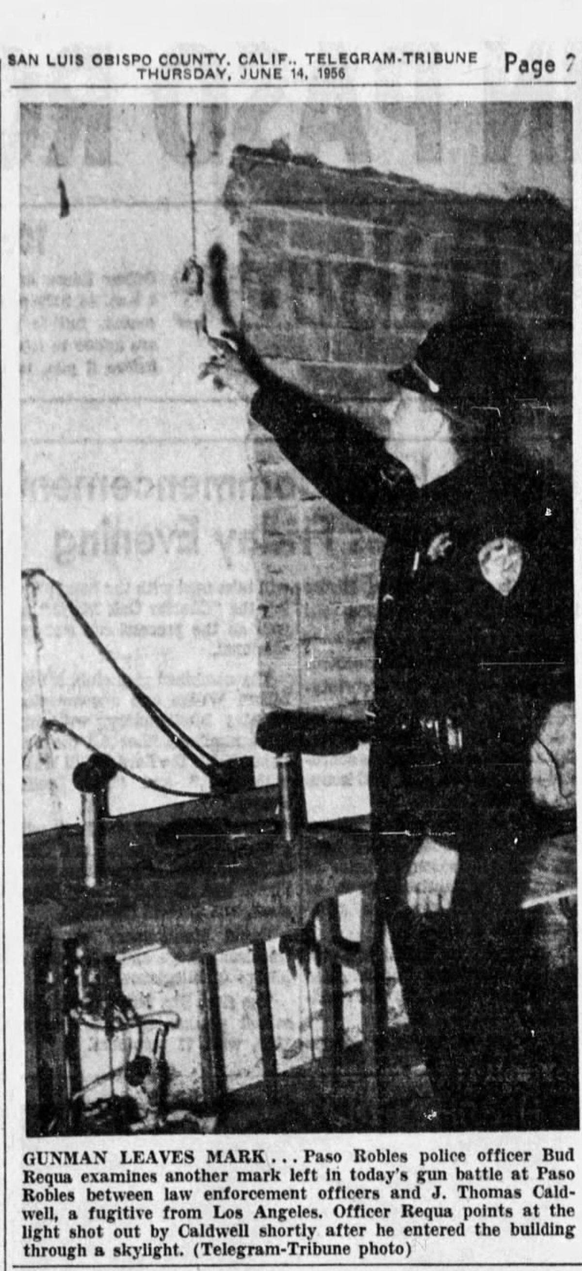 Paso Robles police Officer Bud Requa examines a mark left in a gun battle in Paso Robles on une 14, 1956, between law enforcement officers and J. Thomas Caldwell, a fugitive from Los Angeles. Requa points at the light shot out by Caldwell shortly after he entered the building through a skylight.