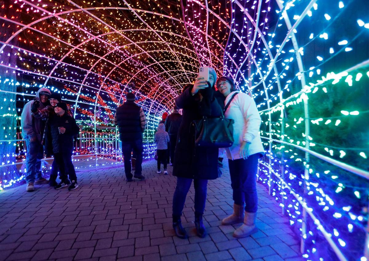 Visitors take selfies in the tunnel of lights at the Cambria Christmas Market on Dec. 14, 2022. The tunnel has become an annual holiday symbol on the Central Coast.