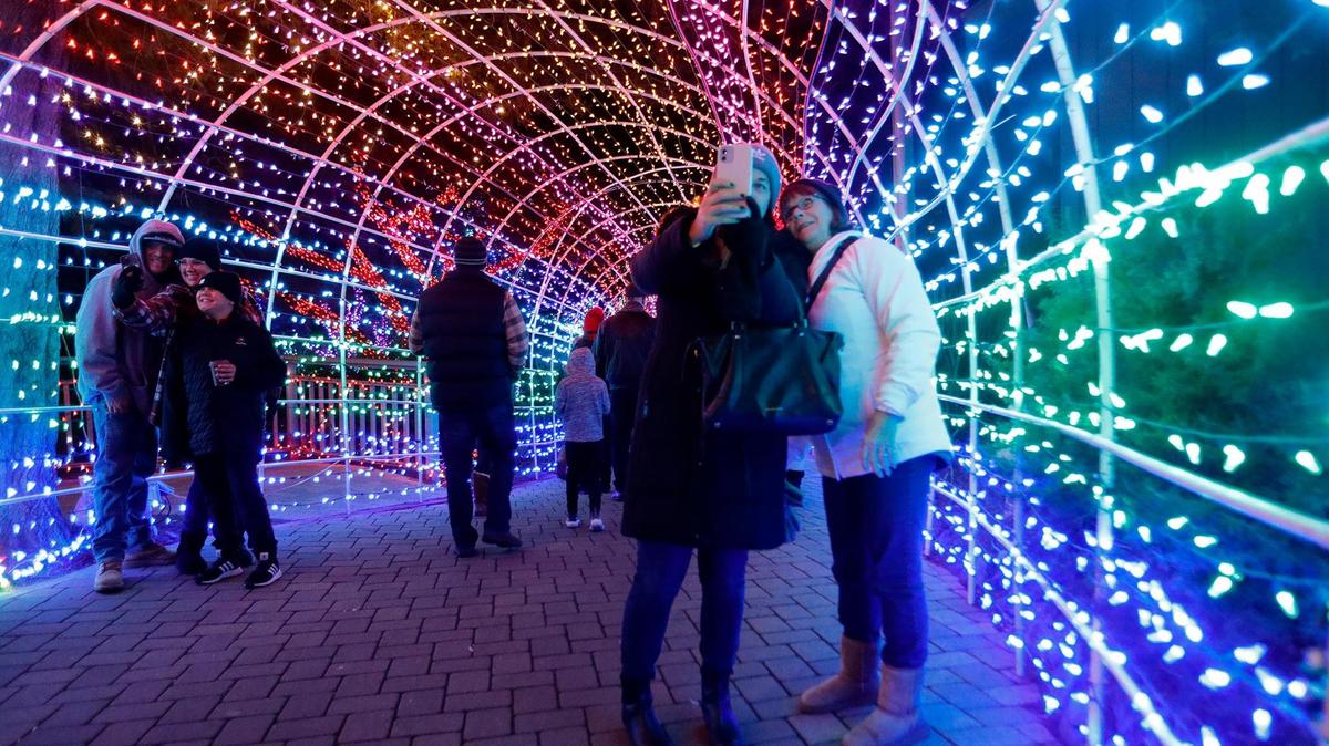 Visitors take selfies in the tunnel of lights at the Cambria Christmas Market on Dec. 14, 2022. Tickets for the popular event went on sale in July 2023.