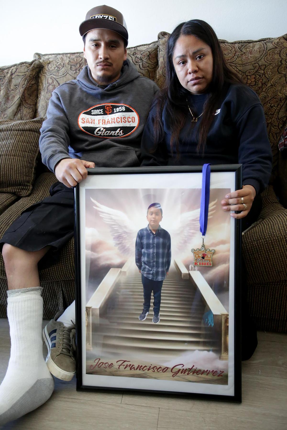 Jose Gutiérrez’s parents, Francisco Gutiérrez and Maria Orozco, sit on their couch with a photo of their son on May 28, 2025.