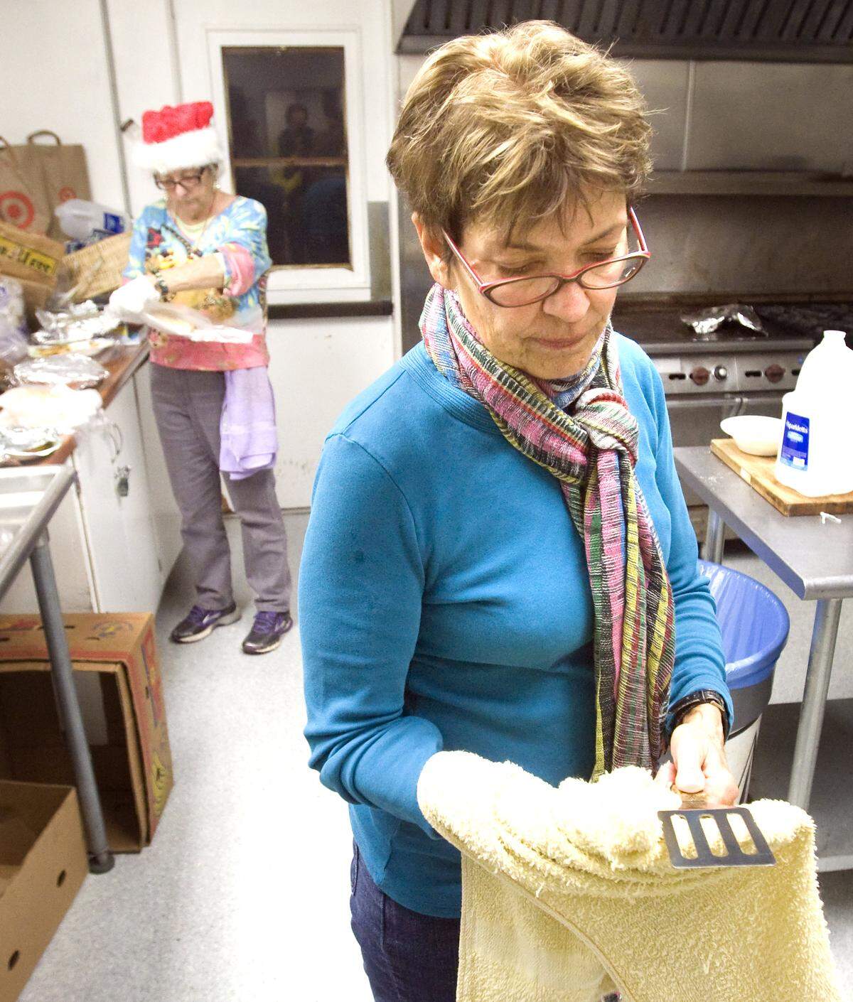 Judy Thompson washes dishes while Nancy Castle, back, preps donated food to be served at the weekly Monday dinner hosted by the Estero Alliance for Care at the Morro Bay Veterans Hall in December 2014.