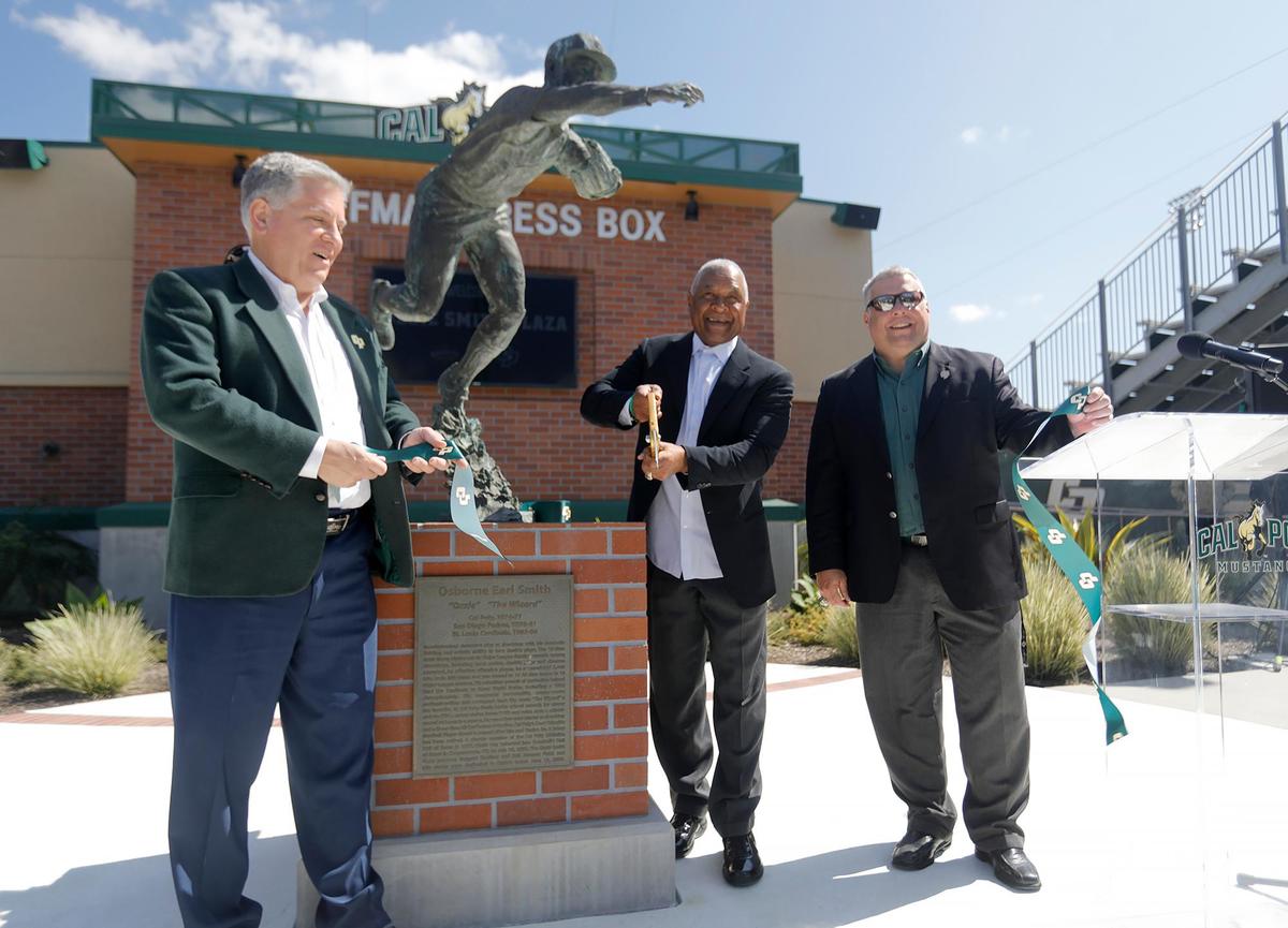 Cal Poly President Jeff Armstrong, left, baseball legend Ozzie Smith and Director of Athletics Don Oberhelman cut the ribbon to re-dedicate Smith’s statue and the plaza at Baggett Stadium in San Luis Obispo on March 25, 2023.