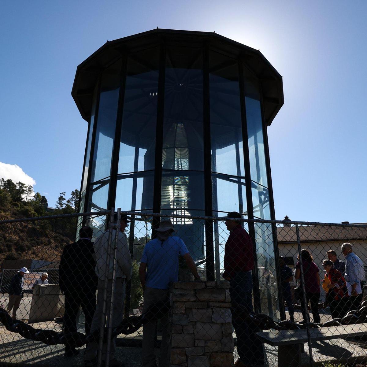 Officials from the Coast Guard and local stakeholders tour the Piedras Blancas Light Station’s historic First Order lens at its enclosure in Cambria, during a tour on Sept. 20, 2022. The protective structure outside the historic lighthouse prism is deteriorating.