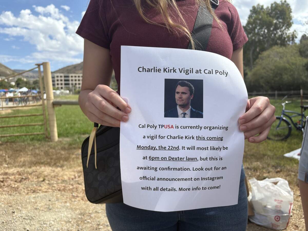 A member of the Turning Point USA club at Cal Poly held up information about a vigil for Charlie Kirk during the university’s club fair on Sept. 17, 2025. The event details were changed, and the vigil is now planned for Sept. 29.