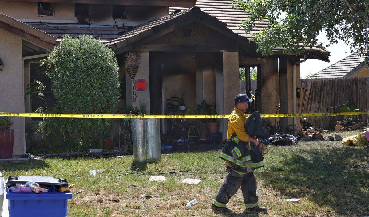 A firefighter walks by the scene of a structure fire involving a home on Sunnyside Way in Templeton on Wednesday, May 18, 2022.