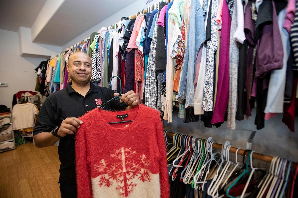 Rogelio Aguilar is the logistic coordinator and ministry director for the SLO Salvation Army. He holds a Christmas sweater in the clothing closet. The clothing is free to clients.