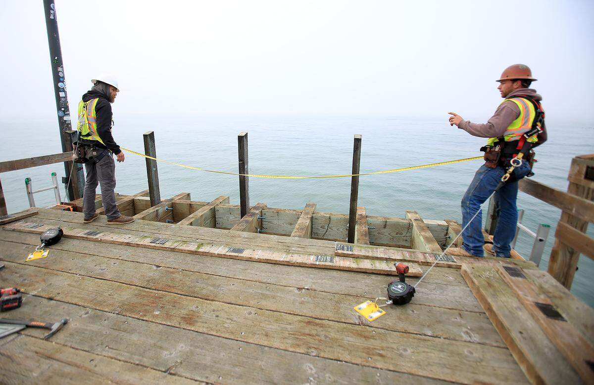 Ben Scilepi, left, and Hank Linder of Hartzell Construction, work to repair a portion of the railing on the damaged Cayucos Pier, on Oct. 31, 2025.