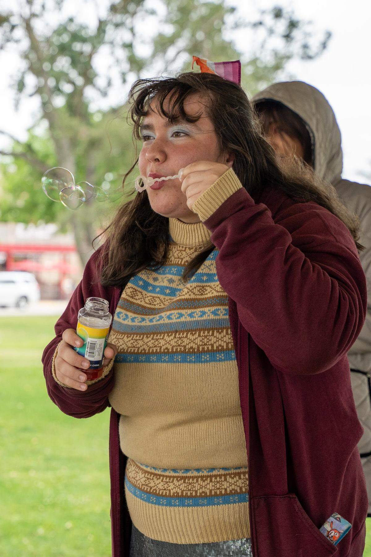 Paso Robles High School Queer Student Union member Bailey blows bubbles at Downtown City Park in Paso Robles on Saturday, May 2, 2026. The Queer Student Union offers community to LGBTQ+ students through after-school events such as a clothing swap held in the park.