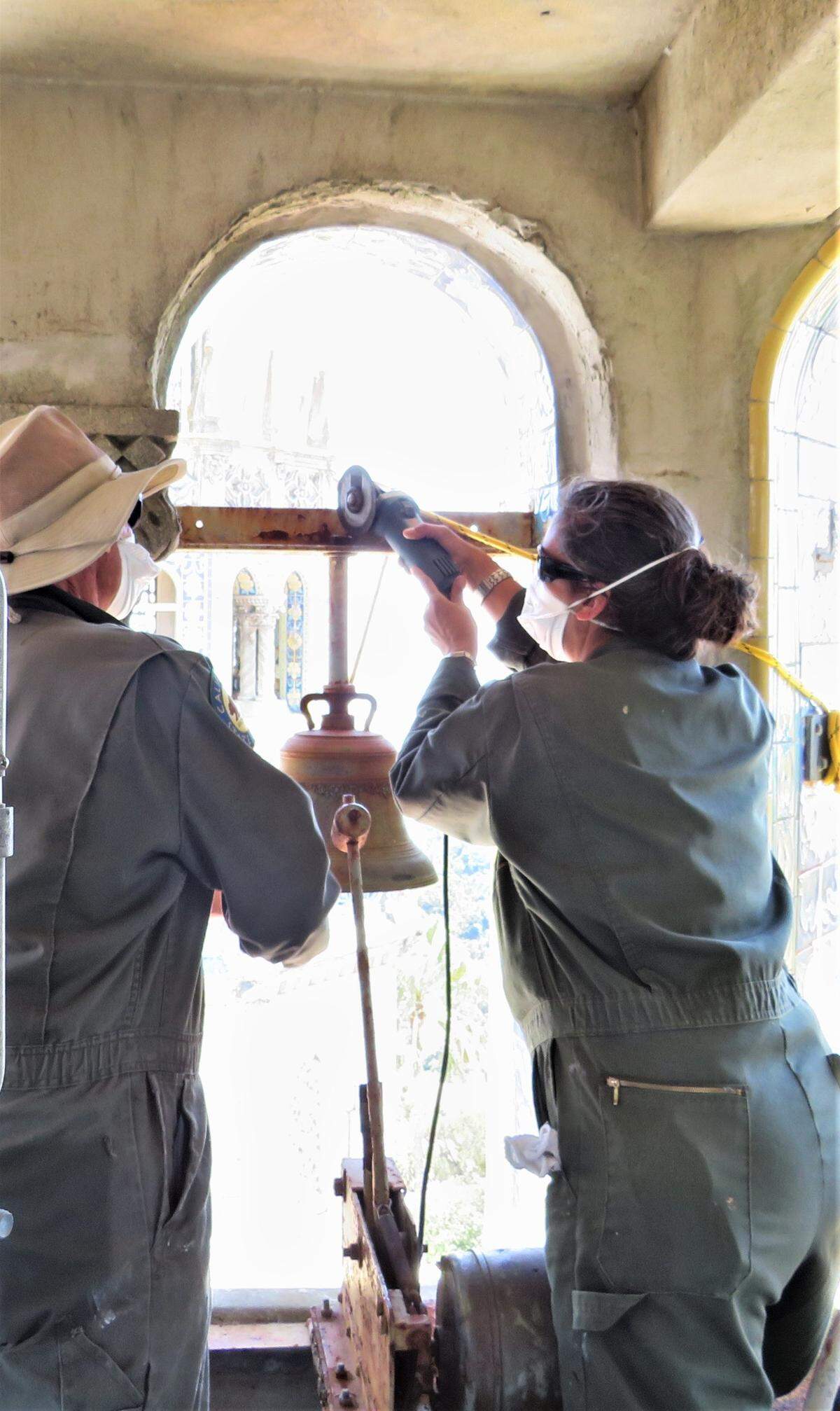 Earnie Riley, at left, and Sarah Graham, state parks historical restoration staffers, remove one of eight of the 36 carillon bells at Hearst Castle that are being rehabilitated, removing rust, other corrosion and other damage from decades of exposure to the elements. Related mechanisms are also being treated and repaired.