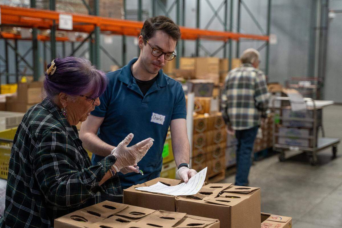 SLO Food Bank volunteers Jude Coren and Charles Schmidt go over a delivery list on Friday, Oct. 31, 2025. The SLO Food Bank is projecting a significant increase in demand for its services while the federal shutdown cuts off SNAP benefits.