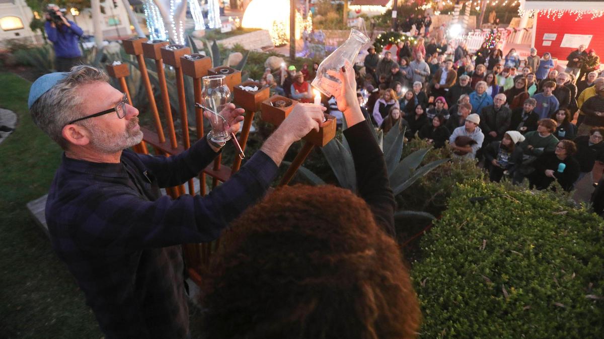 Rabbi Micah Hyman of Congregation Beth David lights a candle on the menorah with the help of San Luis Obispo Mayor Erica Stewart at Mission Plaza on Dec. 7, 2023.