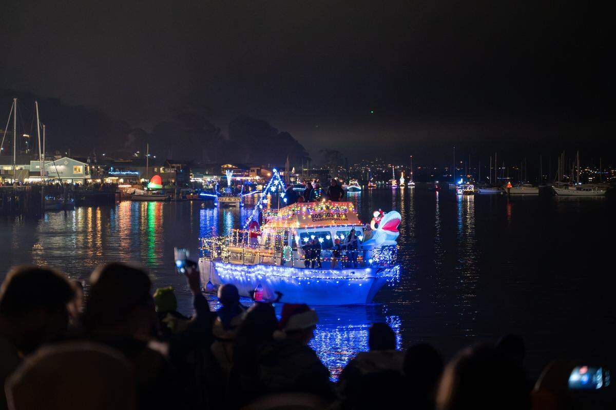 A Morro Bay Whale Watching vessel with a shark masthead arrives for the Morro Bay Lighted Boat Parade on Saturday, Dec. 13, 2025. The parade drew thousands of onlookers and dozens of boats equipped with festive lighting.