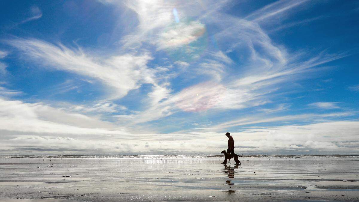 Blue skies came out during a break in the rain on Sunday in Pismo Beach, where Shaun Perisho and dog Bodie strolled along the shore at low tide.