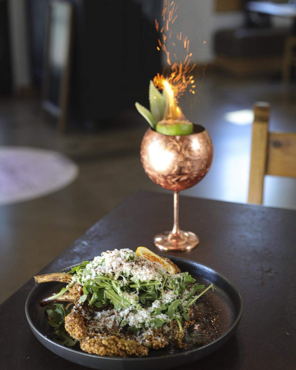 18 oz Pork Chop Milanese, herb panko, capers, arugula, parigiano reggiano, lemon vinigrette and in copper glass is a Belladona, brown butter washed rum, dark rum, Alchemists falernum, pineapple & orange, coconut, charred cinnamon provides sparks. Alchemists' Garden in Paso Robles recently celebrated its fifth year anniversary seen here on July 30, 2025.