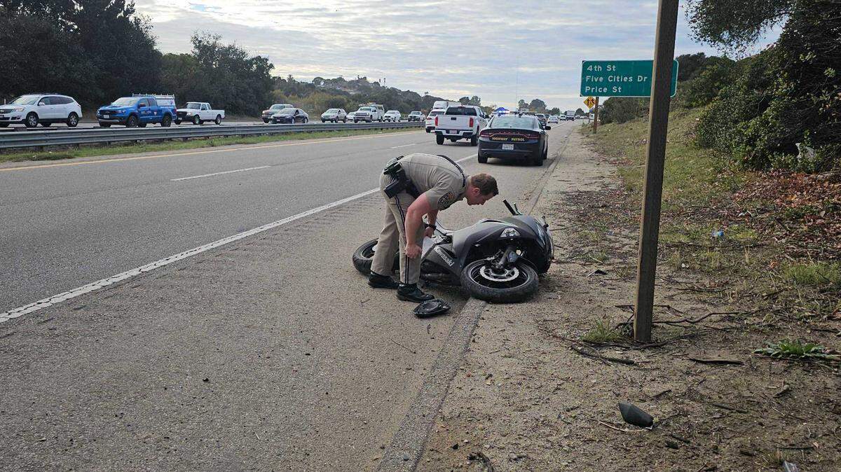 A CHP officer examines a motorcycle under the North Oak Park overpass, after a crash stalled traffic on December 13, 2024.