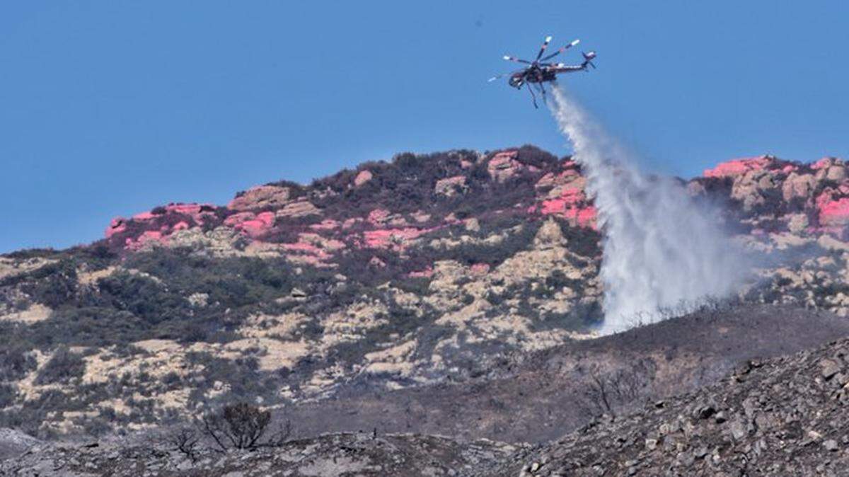 A Sikorsky S-64 Skycrane helicopter douses an Alisal Fire hot spot near W. Camino Cielo on Oct. 16. Firefighters reached 78% containment of the fire along the Gaviota coast by Oct. 17.