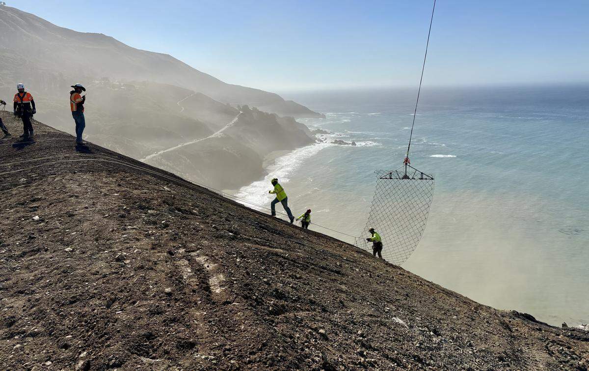 Workers lay cable-net drapery over a hillside at the the site of the Regent’s Slide along the Big Sur Coast in October 2025.