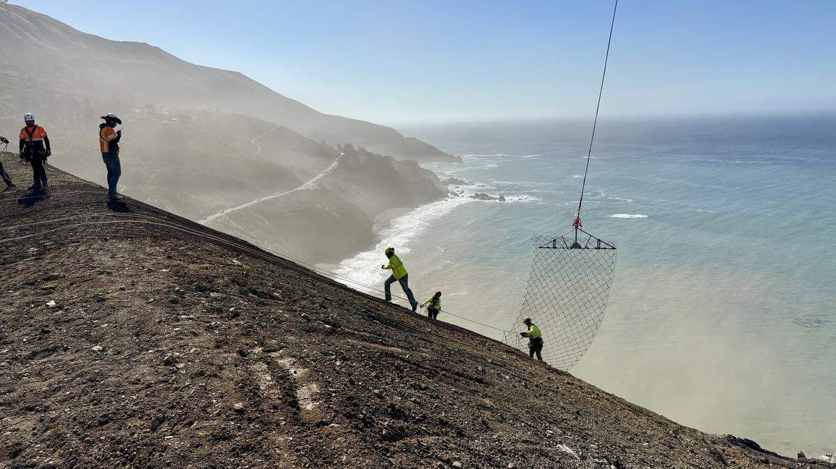Workers lay cable-net drapery over a hillside at the the site of the Regent’s Slide along the Big Sur Coast in October 2025.