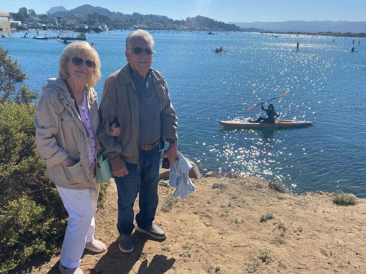 Tom and Gayle Montes pose for a picture with their son Eddy behind them at the 10th annual Witches and Warlocks Paddle in Morro Bay on Sunday, Oct. 29, 2023.