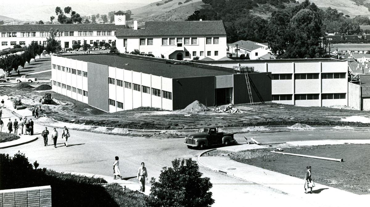 What was known as the Math and Home Economics building is under construction in foreground at Cal Poly in San Luis Obispo. Sept 28, 1959. In the background is the Dexter Library, the first library building on campus. Previously the library had been on the second floor of the clock tower building and to the right surplus military barracks were offices and classrooms before the Robert E. Kennedy Library was built in their place. This viewpoint has been replaced with a wall with the construction the Baker Science building, demolishing the old sprawling science building.