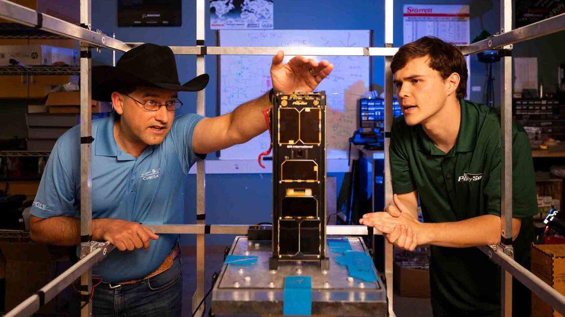 John Bellardo, left, a Cal Poly professor and adviser to the Cal Poly CubeSat program, inspects a CubeSat designed and manufactured at Cal Poly while Ryan Hunter, a computer science and mathematics major, looks on. Cal Poly’s involvement with the mini satellites has been honored with the technology’s induction into the Space Technology Hall of Fame.