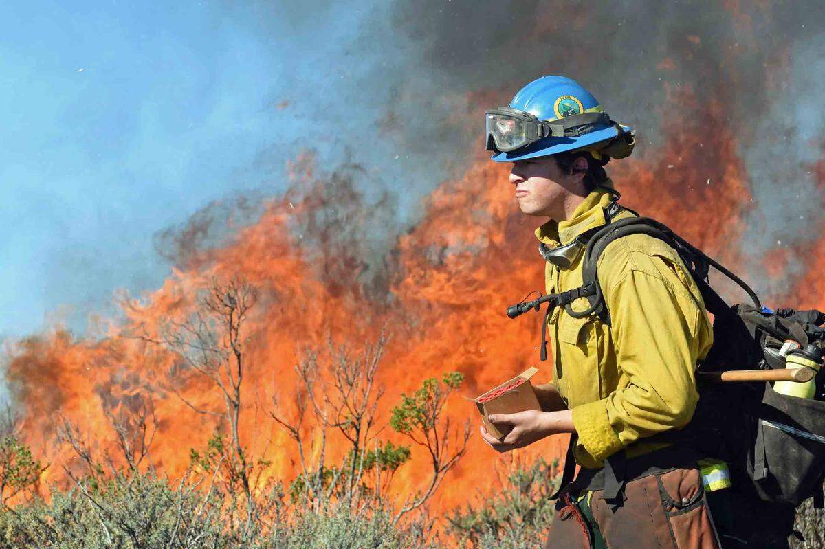 A California Conservation Corps member carries flare cartridges at San Luis Ridge on Friday, Nov. 12, 2021, during a controlled burn operation..