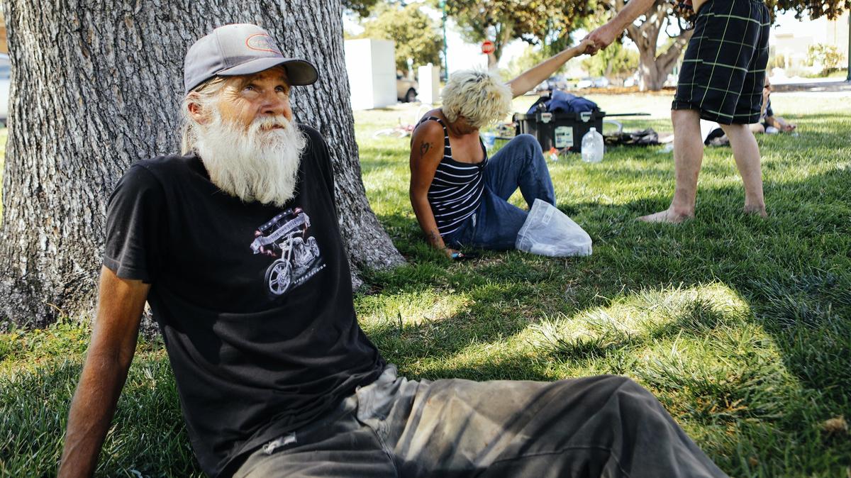 Rick Hurd, left, Makaila Currell and her fiance, Carey Vasquez, rest in the shade of a tree at the Sunken Gardens park in Atascadero in July.