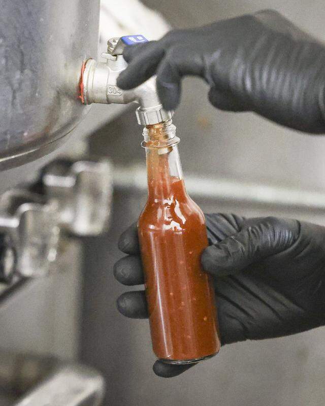 Paul Smith of Smith House Manufacturing bottles Sauce Baby hot sauce in his commercial kitchen in Nipomo on Nov. 10, 2025.
