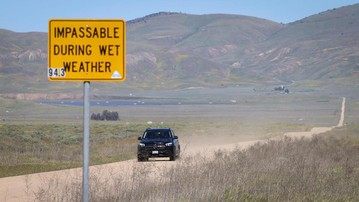 Gold wildflowers bloom on the Temblor Range as a car drives on Seven Mile Road in California Valley on April 3, 2024.