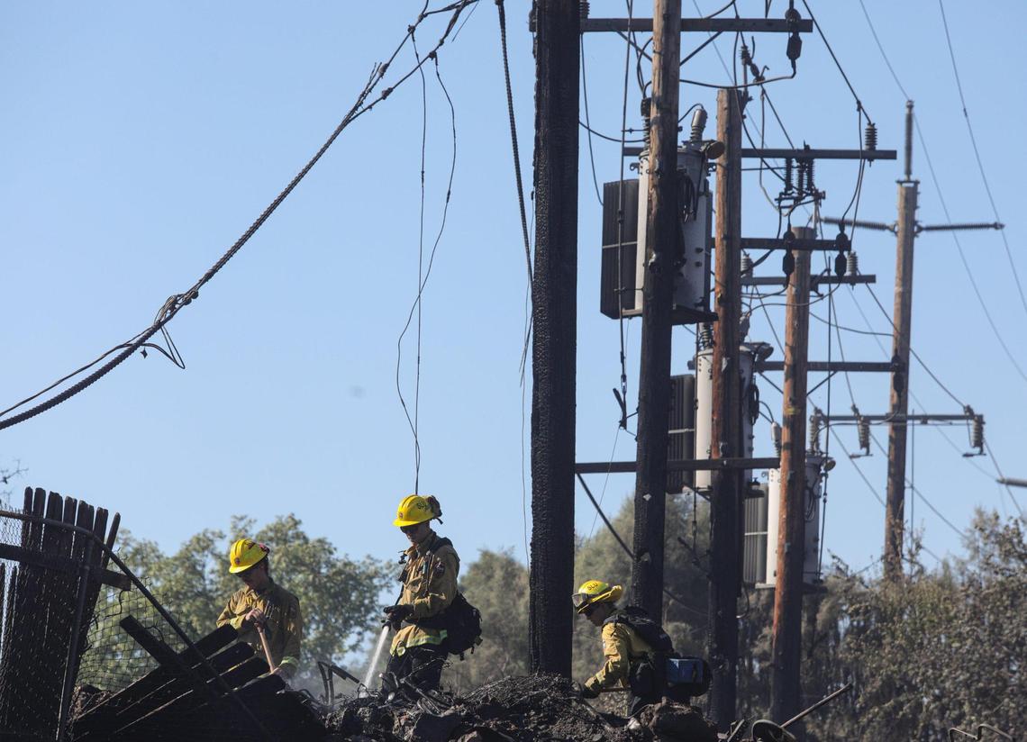 Firefighters from the Park Hill station work under fire-damaged and de-energized power lines in the Capitol Hill neighborhood of Paso Robles. A fire that started in the Salinas River quickly moved uphill.