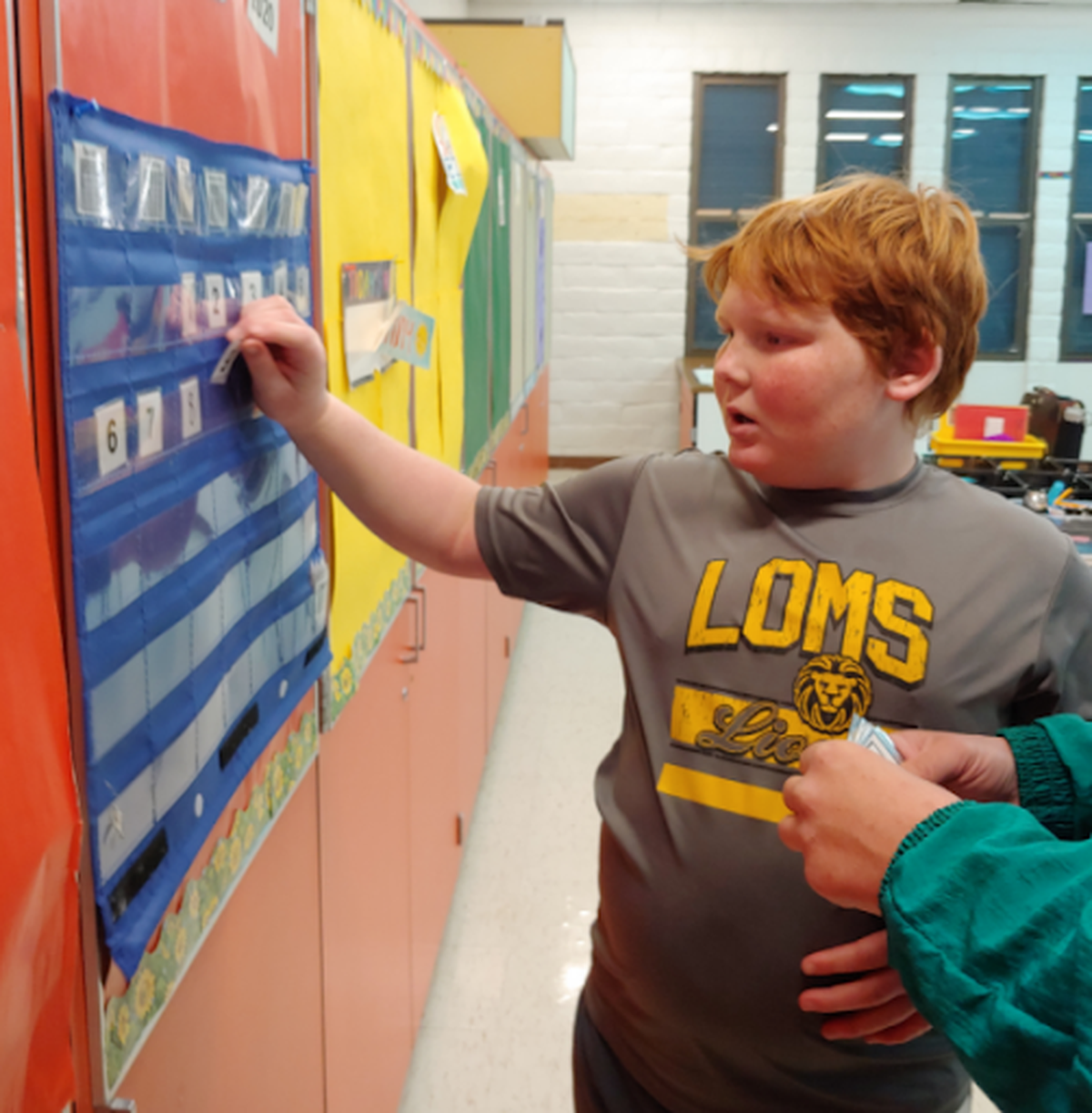 Thor Meier, a student with special needs, fixes the calendar in his classroom at Los Osos Middle School. His teacher, Tiff Buckman, received her first dose of the COVID-19 vaccine on Monday.