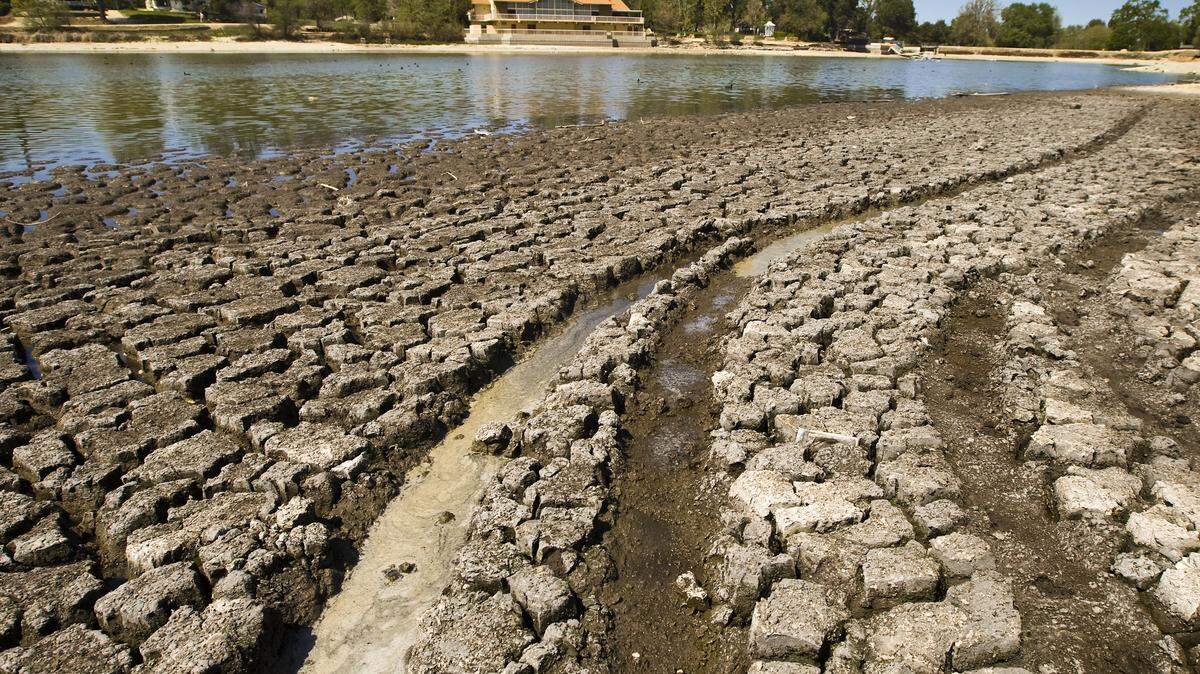 Tire tracks cross the muddy, exposed bottom of Atascadero Lake, which has seen its level drop precipitously over the past year.