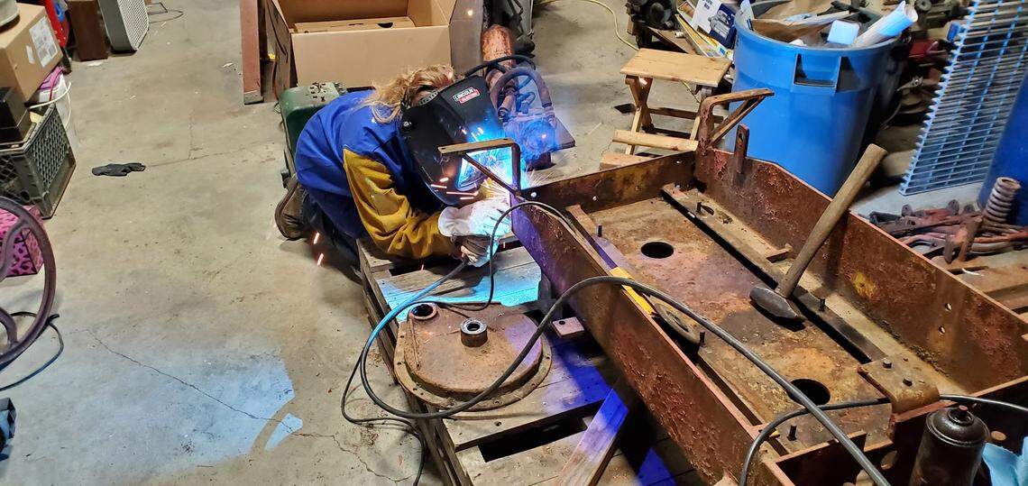 Welding on her Templeton High dozer restoration project puts Mackay Langley, a 17-year-old junior, in an awkward but familiar posture. The completely project will be on exhibit during the school engineering class Makers Faire May 19.