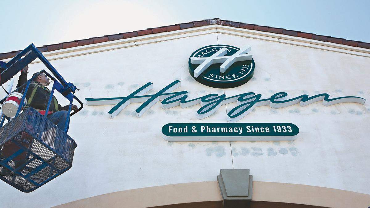 Fred Dominguez checks out his handy work after installing a new sign in front of  a Haggen grocery store, formerly an Albertsons, located in Palmdale, on March 23, 2015.