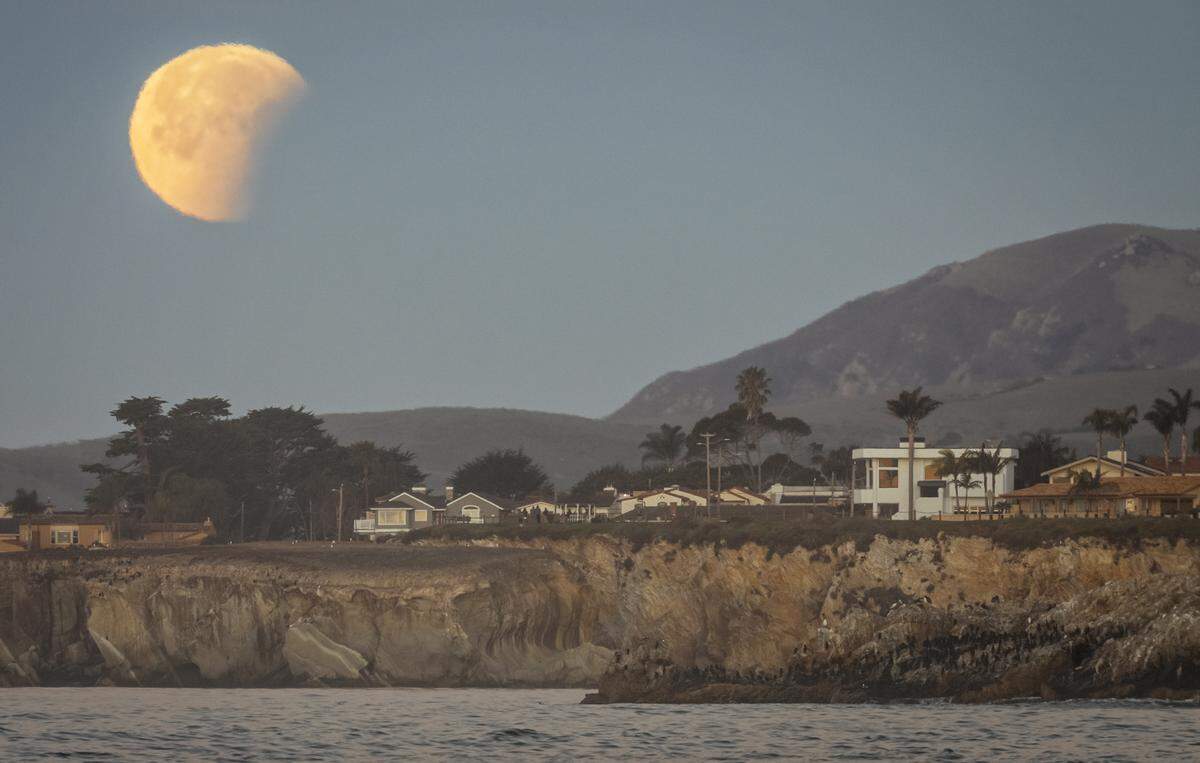 A super blue blood moon sets in partial eclipse over Shell Beach on Jan. 31.