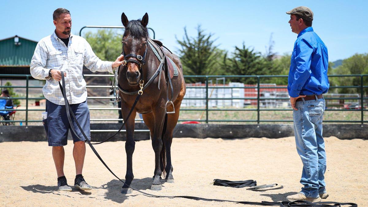 Jeff Baker, U.S. Marine veteran in white shirt, learns two line lead technique in a round pen with “Took” a former race horse that recovered from a broken pelvis. A new equine therapy program for veterans is at Legacy Village treatment center in Nipomo. Elite Vocations Program Director Simon d’Unienville gives instructions.