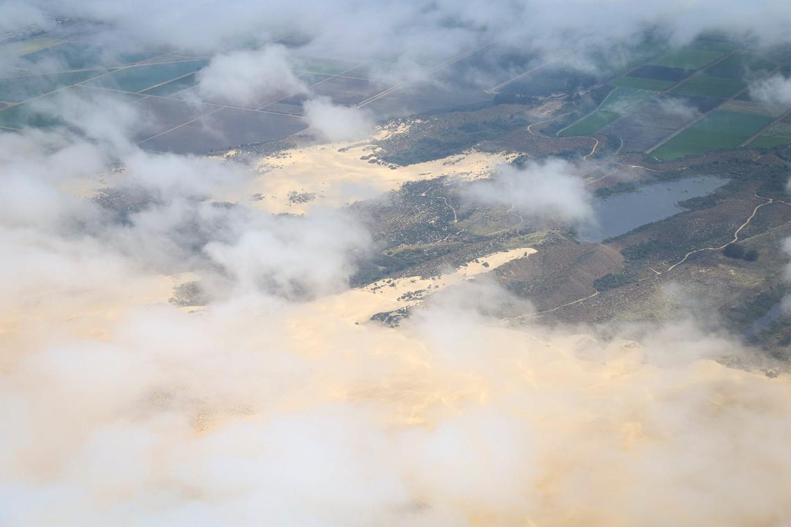 Fog rolls in over the Oceano Dunes, bordered by lakes and farm fields in the background. The Northern Chumash Tribal Council organized an aerial tour of lands bordering the Chumash Heritage National Marine Sanctuary on Sept. 18, 2024. The flight was sponsored by EcoFlight, a nonprofit dedicated to appreciation of the environment.