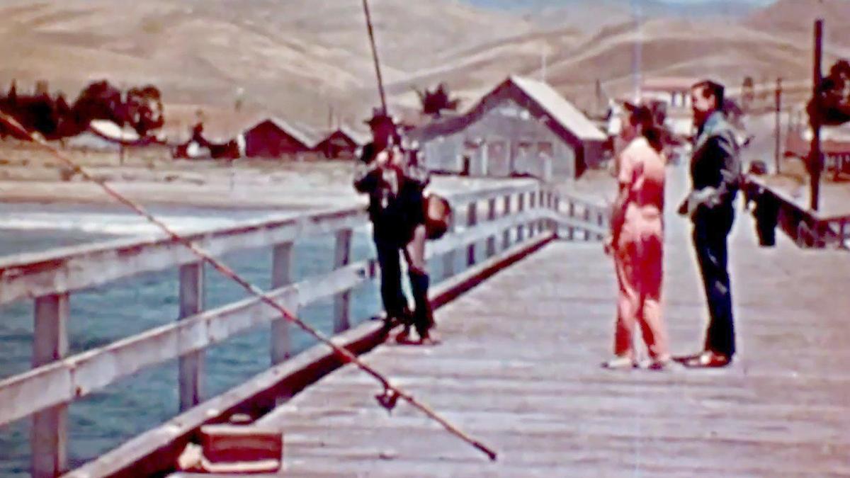 A fisherman shows a couple his catch at the Cayucos Pier with the Cass warehouse that became the Veterans Hall in the background, in a screenshot from the 1938 San Luis Obispo Chamber of Commerce film “Recreation Unlimited.”