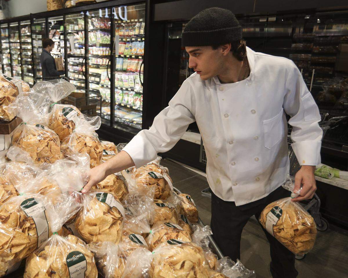 Logan Sanchez sets out tortilla chips. The last days of setup were taking place on Sept. 30, 2025, for the opening of Valley Fresh Market in Atascadero.