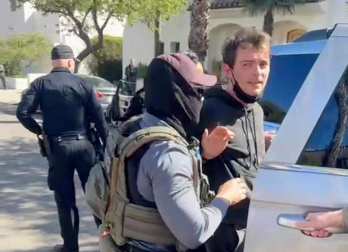 ICE agents escort 26-year-old Jack Randmaa, accused of vandalizing a federal vehicle, into a vehicle on Friday morning, Feb. 20, 2026, outside of the Santa Barbara Police Department station.