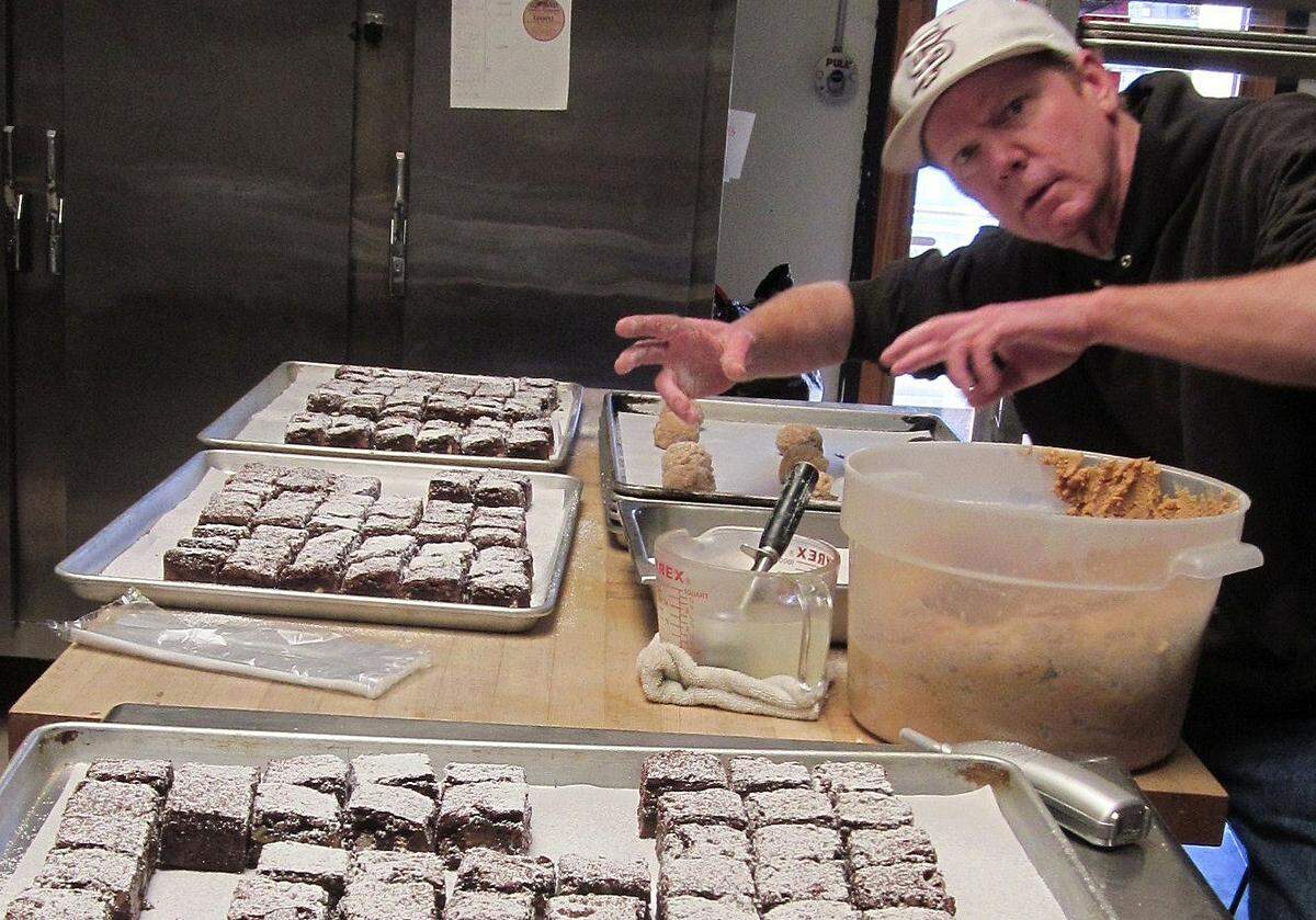 Surrounded by his Red Moose Cookie Company brownies, Roger Wall scoops out hefty portions of dough for the shop’s oversized cookies. He recently sold the shop to the Nichol family of Cambria.