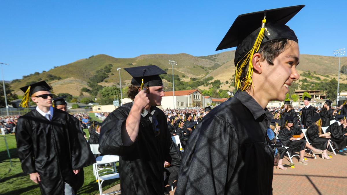 From the left: William Dassler, Link Danninger and Nathan Danner walk to the dais to receive their diplomas. San Luis Obispo High School gave diplomas to the Class of 2021 on the softball field as the traditional football field was under construction.