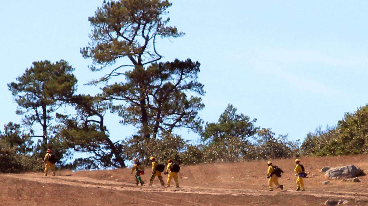 Cal Fire firefighters make their way up a hill north of the Coast Union High School campus, toward the site of a fire that flared Monday afternoon near Cambria.